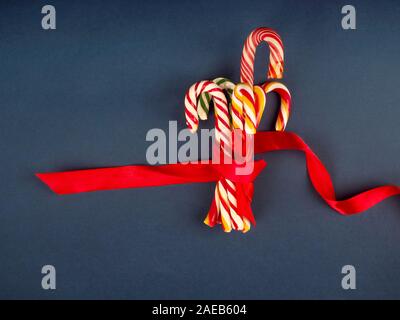 Christmas candy cane. On classic blue background. Flat lay and top view. a handful of Christmas candy cane in a glass jar, with a ribbon Stock Photo