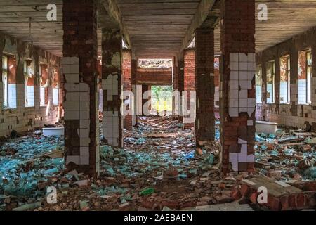 An abandoned and destroyed Soviet-era building made of brick with broken glass blocks. Stock Photo