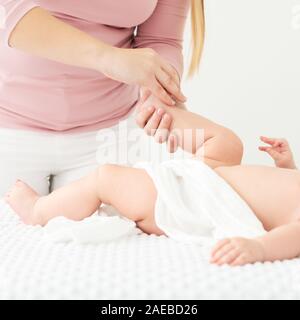 Baby massage. Female therapist gently massaging babys foot. Doctor examining infant baby boy. Stock Photo
