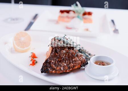 Grilled flounder with lemon and savory sauce on restaurant table, toned image