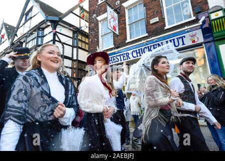 Rochester, UK.  8 December 2019.  Participants walk through a 'snow storm' during the annual Dickensian Christmas Festival in Rochester.  The Kent town is given a Victorian makeover to celebrate the life of the writer Charles Dickens (who spent much of his life there), with Victorian themed street entertainment, costumed parades and a Christmas market.  Credit: Stephen Chung / Alamy Live News Stock Photo