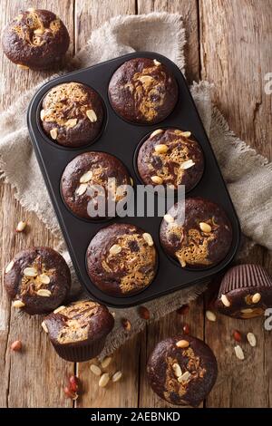 Chocolate muffins with peanut butter and nuts in a baking dish on the table. Vertical top view from above Stock Photo