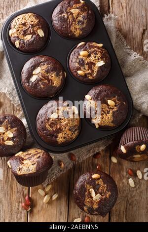 Chocolate peanut muffins in a baking dish on the table. Vertical top view from above Stock Photo