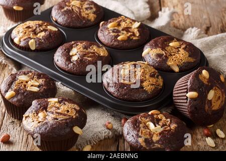 Freshly baked chocolate muffins with peanut butter and nuts in a baking dish on the table. horizontal Stock Photo