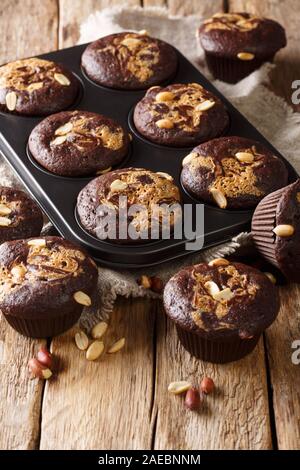 Chocolate muffins with peanut butter and nuts in a baking dish on the table. vertical Stock Photo