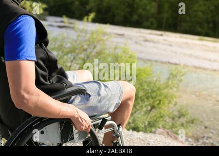 Happy young man in wheelchair outside in nature on a sunny summer day Stock Photo