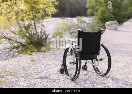 Empty wheelchair standing in a park on walking path Stock Photo