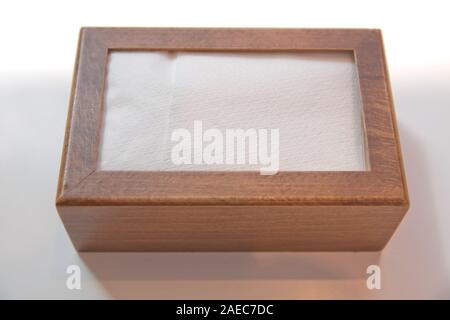 Wooden napkin holder with paper serviettes . Wooden brown empty napkin box . wooden stand with salt shaker, napkins on a wooden table in a cafe . Stock Photo