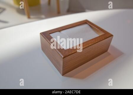 Wooden napkin holder with paper serviettes . Wooden brown empty napkin box . wooden stand with salt shaker, napkins on a wooden table in a cafe . Stock Photo