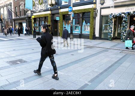 Trendy young Chinese teen girl walking past Tiffany & Co. store at Christmas time on Old Bond Street in Mayfair London W1 England UK  KATHY DEWITT Stock Photo