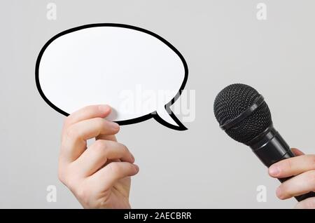 Hands holding a blank speech bubble and microphone. Conference, interview or social media concept with microphone and blank speech bubbles Stock Photo