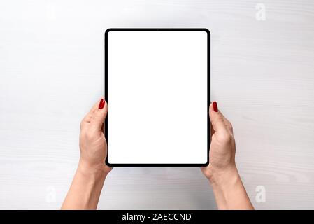 Tablet mockup. Girl holding tablet in vertical position abowe white desk. Flat lay, top view Stock Photo