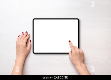 Tablet on desk in horizontal position and isolated screen for mockup, app or web site presentation. Girl touch display concept. Top view, flat lay Stock Photo