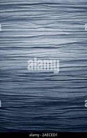 Close-up of a creased and backlit paper lampshade with blue hue. High resolution full frame textured background. Stock Photo