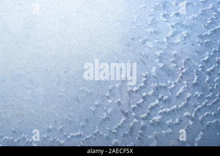 Surface of a winter frozen window is backlit by the sun outside, background, texture. Stock Photo