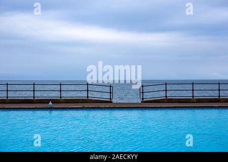 Swimming pool and sea with access in railing on the promenade in Llandudno Gwynedd Wales UK Stock Photo