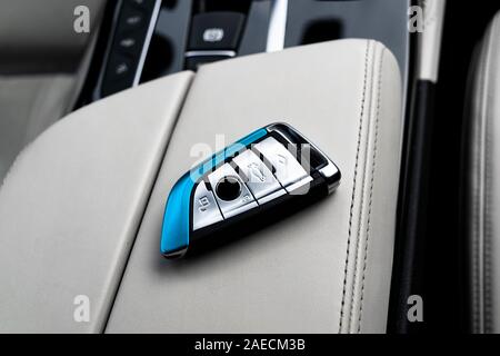 Closeup inside vehicle of wireless key ignition on white perforated leather seat. Wireless start engine key. Car key remote isolated. Modern Car keys Stock Photo