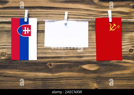 Hanging flags of Slovakia and Soviet Union attached to rope with clothes pins with copy space on white note paper on wooden background.Diplomatic rela Stock Photo