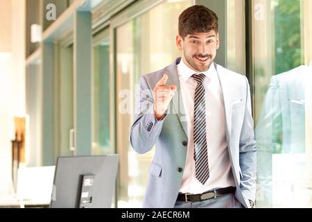 Portrait of successful businessman wearing suit and tie while standing in the office and pointing at you. Stock Photo