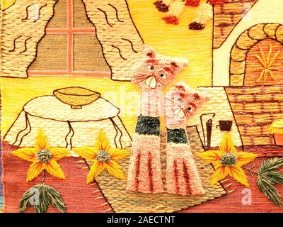 Beautiful embroidery with various bright threads. Two beautiful and fluffy cats are sitting in a house by the fireplace. Stock Photo