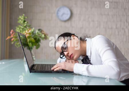 Overworked tired woman sleeping on desk at laptop in office Stock Photo