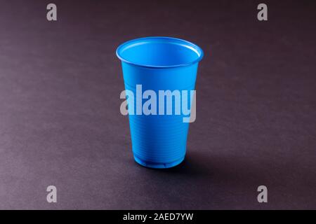Blue empty plastic cup on a black background. Recycling plastic. Plastic waste. Stock Photo