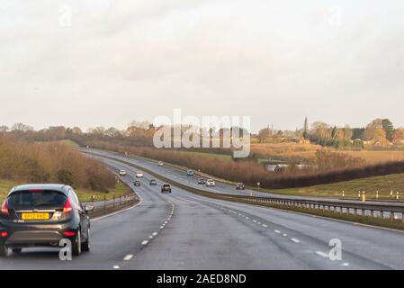 Vehicles driving on a stretch of A130 three lane carriageway with Rettendon on horizon with dip in the road near Runwell, Essex, UK. Damp winter drive Stock Photo