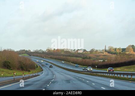 Vehicles driving on a stretch of A130 three lane carriageway with Rettendon on horizon with dip in the road near Runwell, Essex, UK. Damp winter drive Stock Photo