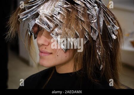 Beautiful young woman with foil on her hair. Bleaching or dyeing process. Beauty salon, fashionable hair coloring Stock Photo