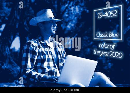 young handsome attractive man sitting on the sandy tropical exotic beach on a summer resort working on a laptop Stock Photo