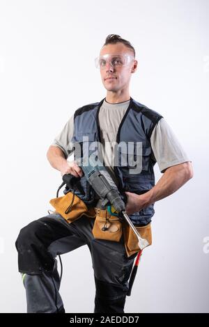 Builder with a drill in his hands, in safety glasses. Stock Photo