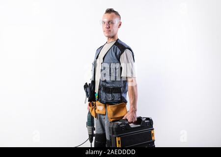Builder with tools in cases. In a helmet and glasses, and unloading. Stock Photo