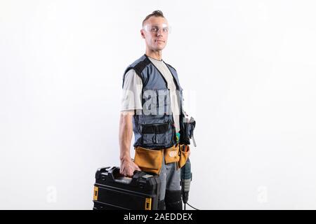 Builder with tools in cases. In a helmet and glasses, and unloading. Stock Photo