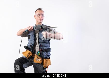 Builder with a drill in his hands, in unloading, aims to the right. Stock Photo