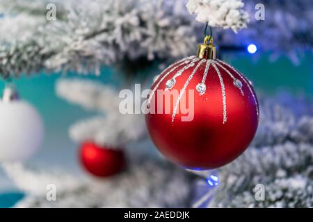 A red Christmas Bauble with glitter on hanging on a frosty Christmas tree Stock Photo