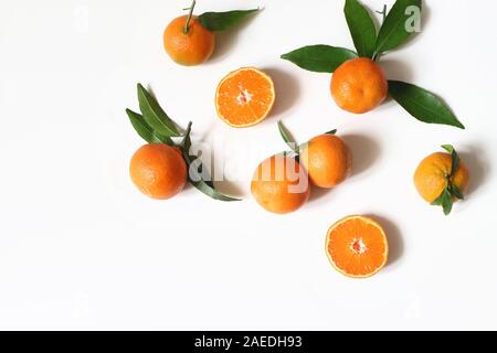 Styled stock photo. Decorative summer fruit composition. Whole and sliced orange tangerines, citrus fruit and leaves isolated on white table Stock Photo