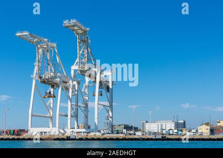 Container cargo gantry Super-Post Panamax cranes lined up at empty dock in Oakland Harbor on sunny day under blue sky - Oakland, California, USA - Cir Stock Photo