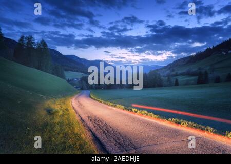 Blurred car headlights on rural road at night in summer Stock Photo