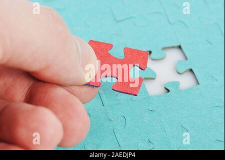 Red puzzle piece in hand macro close up view on game background Stock Photo