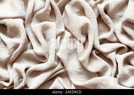 Folds of natural gray beige fabric, top view, background or concept. Stock Photo