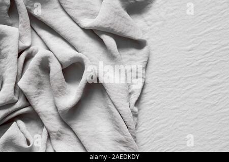 Folds of natural gray beige fabric, top view, background or concept. Stock Photo