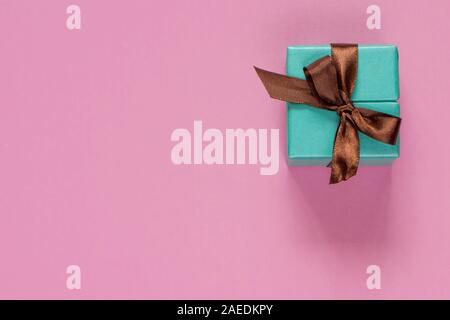 Turquoise gift or present box with brown ribbon on pink table top view. Flat lay. Birthday, wedding or christmas concept. Stock Photo