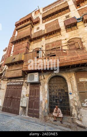 Arabic senior sitting on the steps in front of the door of a coral town house in the historic district Al Balad in Jeddah, KSA, Saudi Arabia Stock Photo