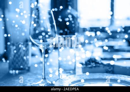 Holiday party blurred background made from decorated table with bouquet of flowers and colorful lights bokeh. Selective focus. Christmas dinner. Classic Blue color 2020 concept. Stock Photo