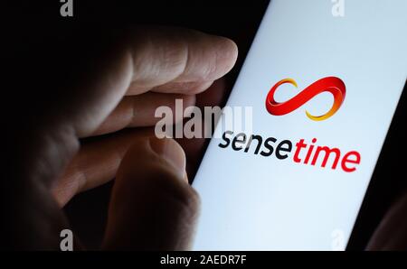 SenseTime logo on a glowing screen and a hand pointing at it. Stock Photo