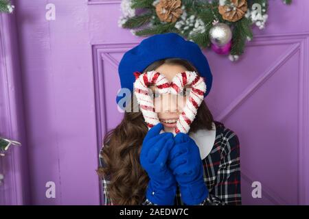 Christmas decor. Peppermint candy. Decorating ideas. Child hold christmas candy cane. Create decorations. Striped candy cane traditional winter holidays. Elegant kid in hat and gloves. Treat yourself. Stock Photo