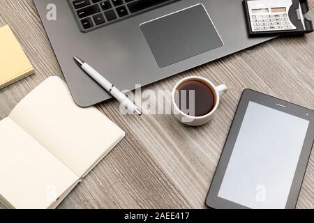 Coffee cup on a work table with laptop, notebook, calculator and tablet. Top view Stock Photo