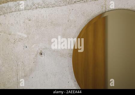 Concrete cement wall in the room with round shape mirror. Stock Photo
