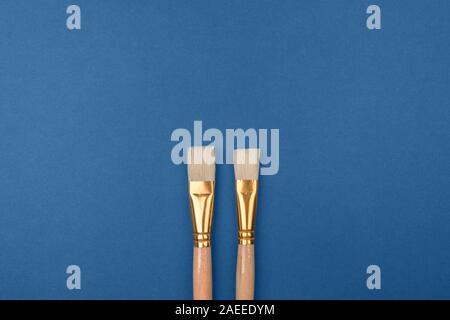 Two brushes is a warm color with a natural bristle brush on the blue cold background.  Stock Photo