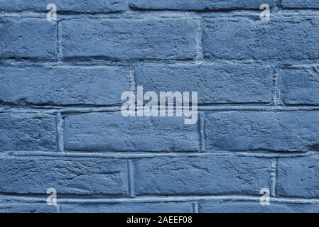 Cracked and textured blue wall, brick wall background. Color of the year 2020 concept. Close up. Fashionable classic blue color of spring-summer 2020 season from New York fashion week. Stock Photo